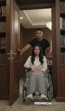 A man pushes a woman in a wheelchair through a library door.